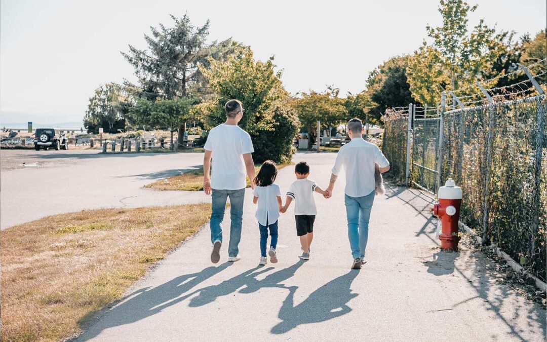 Parents holding hands with two children taking a walk.